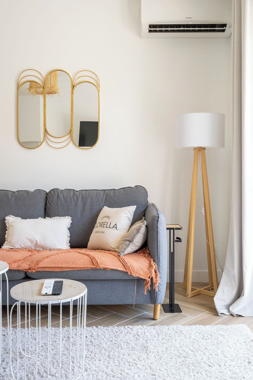 Una sala de estar moderna con un sofá gris, una lámpara blanca y una mesa de centro redonda.