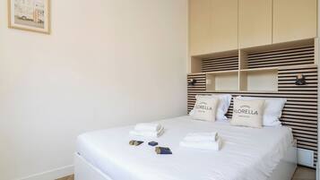A neatly made bed with pillows, a framed picture on the wall, and a built-in wardrobe with horizontal slats.