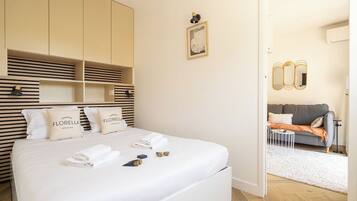 Ein Hotelzimmer mit einem großen Bett, einem Kleiderschrank, einem kleinen Tisch und einer Couch im angrenzenden Wohnbereich.