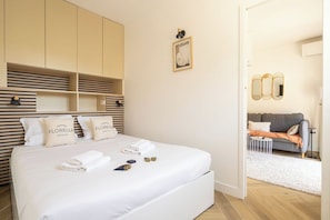 Hotellihuoneessa on suuri sänky, vaatekaappi, pieni pöytä ja sohva, joka sijaitsee viereisessä oleskelutilassa.