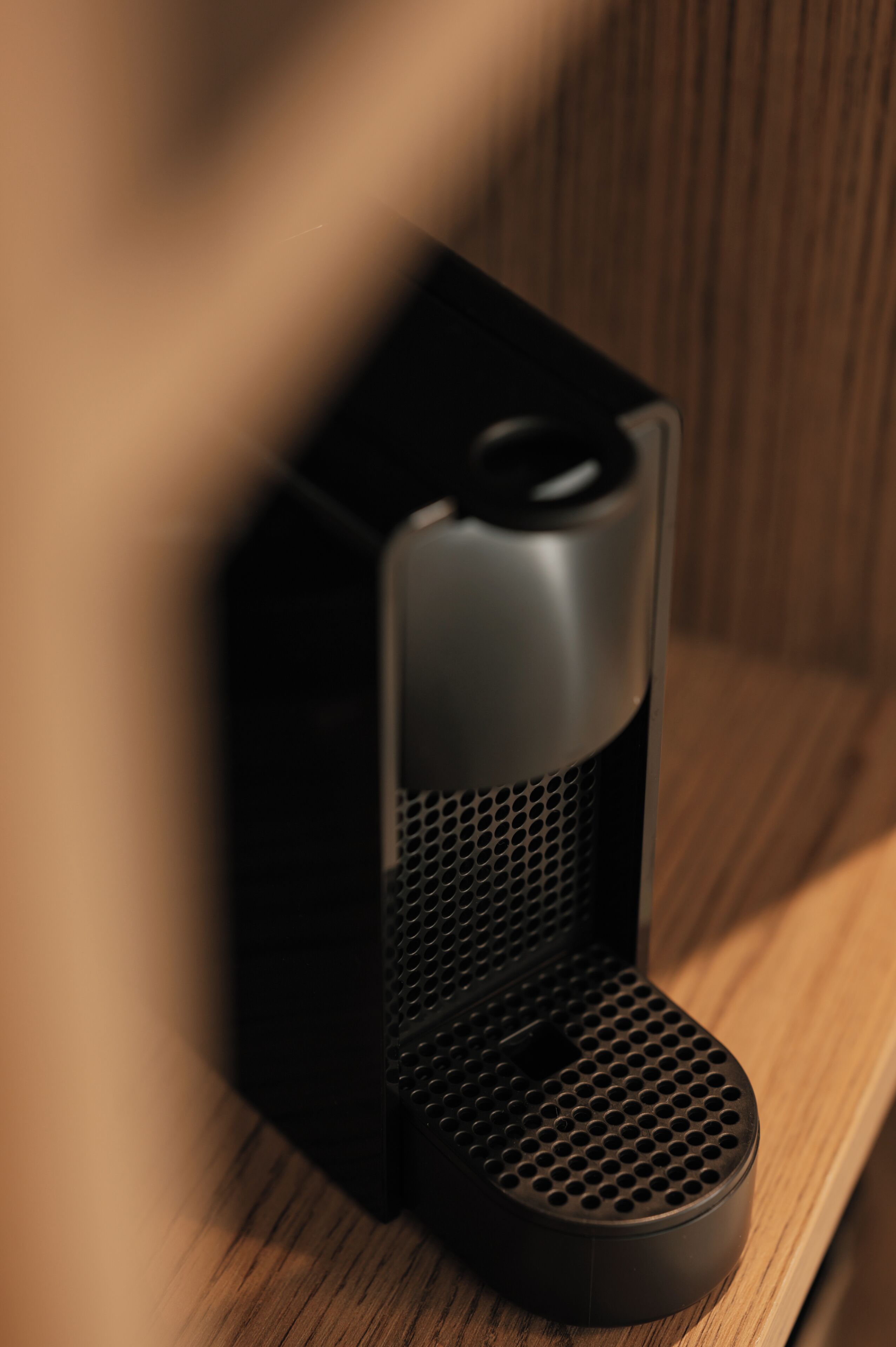 A black coffee maker on a wooden surface.