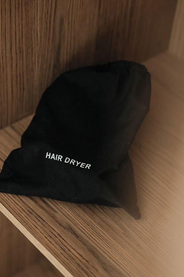 A black bag labeled "HAIR DRYER" on a wooden shelf.