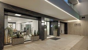 Un moderno vestíbulo de hotel con un espacio amplio, una recepción y una escalera visible que conduce a plantas superiores.