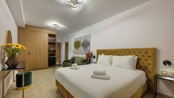 A modern hotel room with a large bed, a wooden wardrobe, a green sofa, and a small table with a vase of flowers.