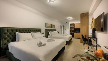 A hotel room with two beds, a desk, and a kitchenette.