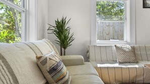 Un salón acogedor con un sofá color beige, cojines a rayas y una planta en maceta.