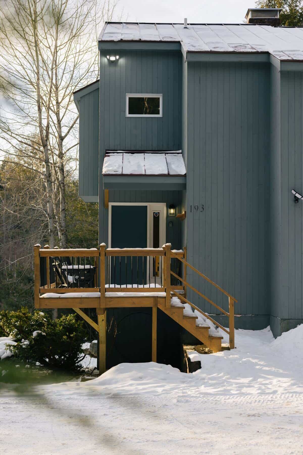 Un bâtiment à deux étages doté d’une terrasse en bois et d’un escalier menant à l’entrée.