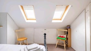 A room with two skylights, a bed, two wooden chairs, a small table, and a wardrobe. - 3 Bedroom - 1 Bathroom - Garden - Pet Friendly (Wrexham)