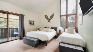 Ein Schlafzimmer mit zwei Betten, einem großen Fenster und einem Balkon.