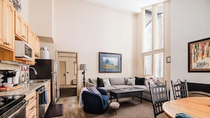 Eine moderne Küche mit Holzausstattung, einer Mikrowelle und einem Herd. Es gibt einen Essbereich mit Tisch und Stühlen, ein Sofa und einen Teppich.