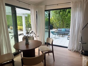 A modern dining area with a round table, chairs, and a vase with flowers.