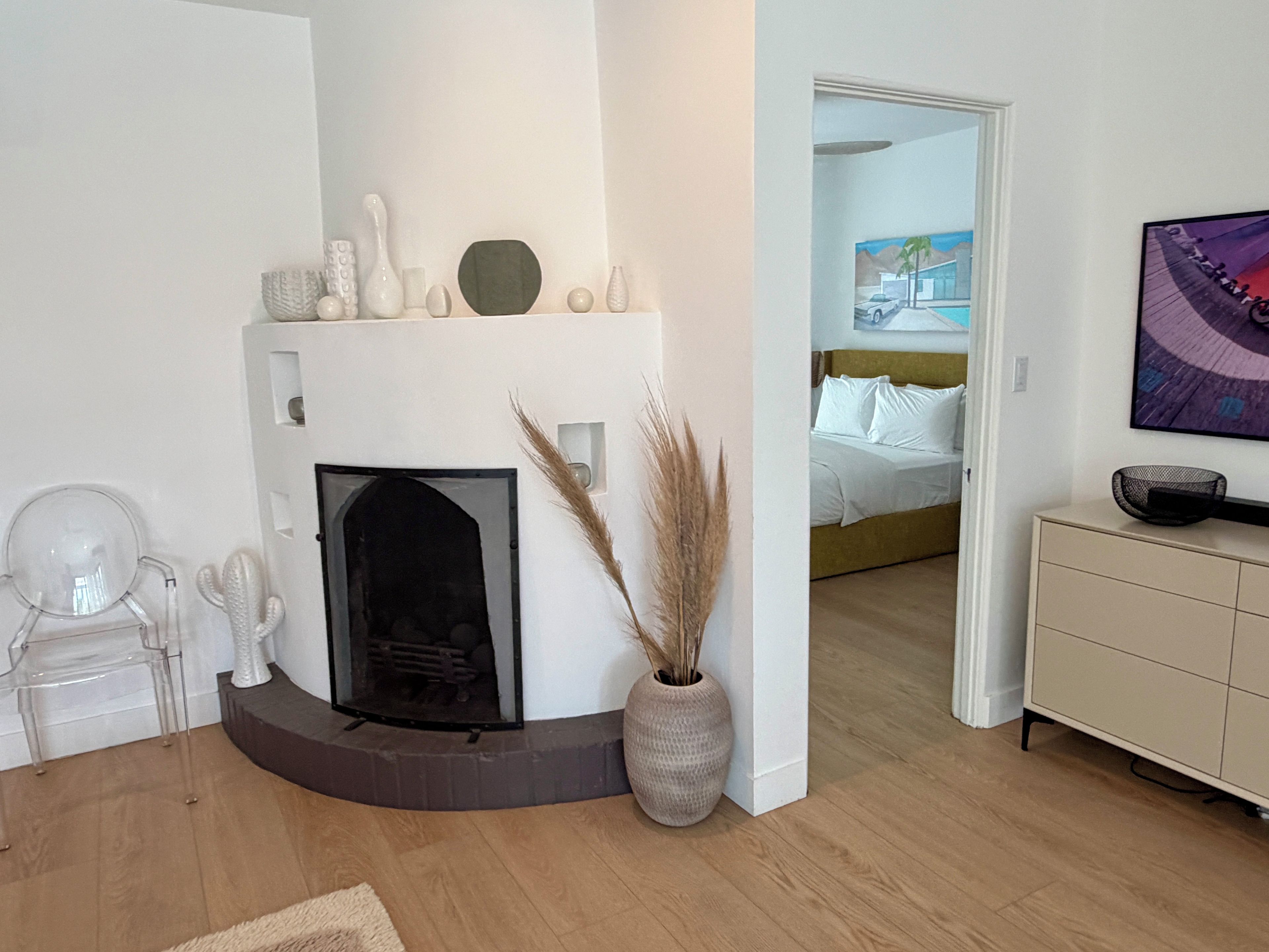 Een moderne woonkamer met een open haard, een bank, een eettafel en een schilderij aan de muur.