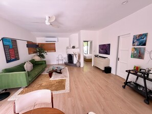 A modern living room with a green sofa, a glass coffee table, and a fireplace. - The Knot - The Ultimate Palm Springs Bungalow (Palm Springs)
