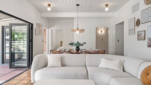 Una sala de estar moderna con un sofá modular, una mesa de comedor con sillas y un ventanal con vistas a zonas verdes.