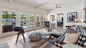 A spacious living area with a large glass door leading to an outdoor patio, a round coffee table, a sofa, and a chair.