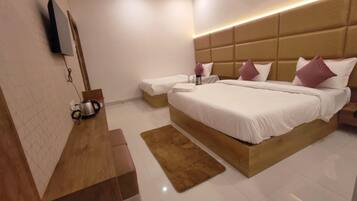 A modern hotel room with a large bed, a bedside table, a flat-screen TV mounted on the wall, and a ceiling fan.