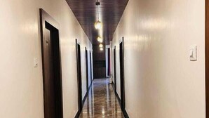 A long, narrow hallway with a polished floor, dark wooden ceiling, and multiple doors on each side. - Hotel Kashni (Maihar)