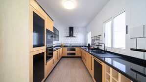 A modern kitchen with wooden cabinets, black countertops, and a central island.