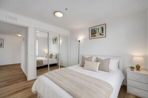 Ein Schlafzimmer mit einem Bett, Nachttischen, einem Spiegel und einem Bild an der Wand.