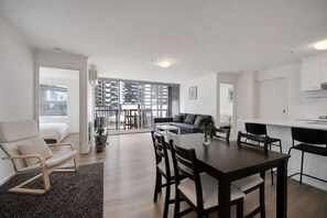 A modern apartment with a dining area, sofa, and kitchen.