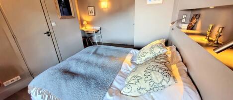 A bedroom with a bed, a desk, and a chair.