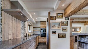 A modern kitchen with wooden accents, a stone accent wall, and artwork on the walls. - Ski-in/ski-out chalet with pool and sauna in Val-d'Isère (Val-d'Isère)
