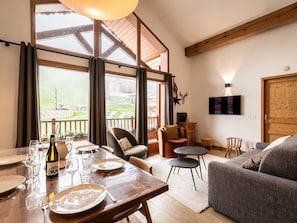 Un coin repas avec une table dressée pour quatre personnes, un canapé et un téléviseur fixé au mur.