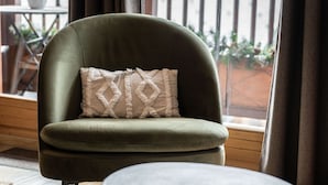 A green armchair with a patterned cushion, a small round table, and a view of a balcony with plants. - Renovated duplex in center with parking and wifi (La Plagne Montalbert)