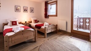 A hotel room with two wooden beds, a large window with a view, a ceiling light, and a radiator. - Renovated duplex in center with parking and wifi (La Plagne Montalbert)