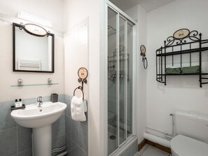 A bathroom with a white sink, a glass shower enclosure, and a toilet.