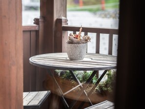 A round wooden table with a decorative stone planter containing a pine cone and branches.