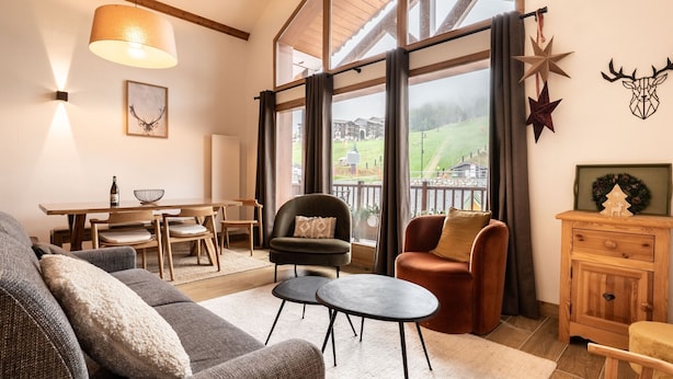A spacious living room with a high ceiling, large windows, and a view of a green landscape. - Renovated duplex in center with parking and wifi (La Plagne Montalbert)