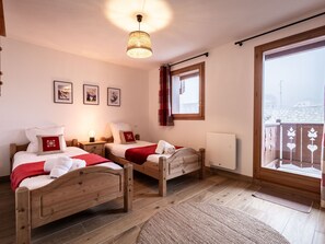 Une pièce avec deux lits en bois, une fenêtre avec des rideaux, un radiateur et un luminaire fixé au mur.