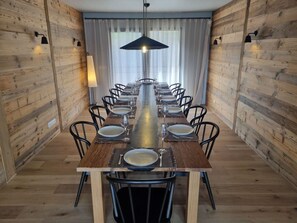 A long dining table with chairs, set with plates and glasses, in a room with wooden walls and a hanging light fixture. - Luxury chalet with jacuzzi, sauna, 8 br, La Plagne Montalbert (La Plagne Montalbert)