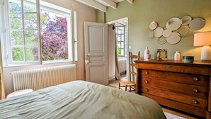 A bedroom with a bed, dresser, and a window with a view of trees. - Peaceful Berry retreat with garden and fireplace (Brives)