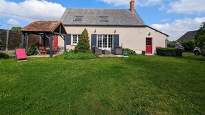 A two-story house with a sloped roof, a chimney, and a small attached garage. - Peaceful Berry retreat with garden and fireplace (Brives)