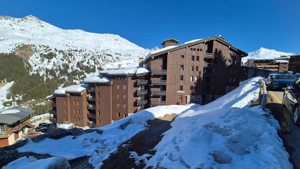 Ein mehrstöckiges Hotel mit Skipiste im Hintergrund.