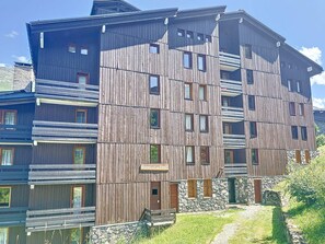 A multi-story wooden building with balconies, a stone base, and a sign indicating a restaurant.