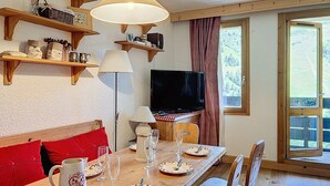Ein gemütlicher Essbereich mit Holzmöbeln, einem Fernseher und Regalen mit diversen Gegenständen.