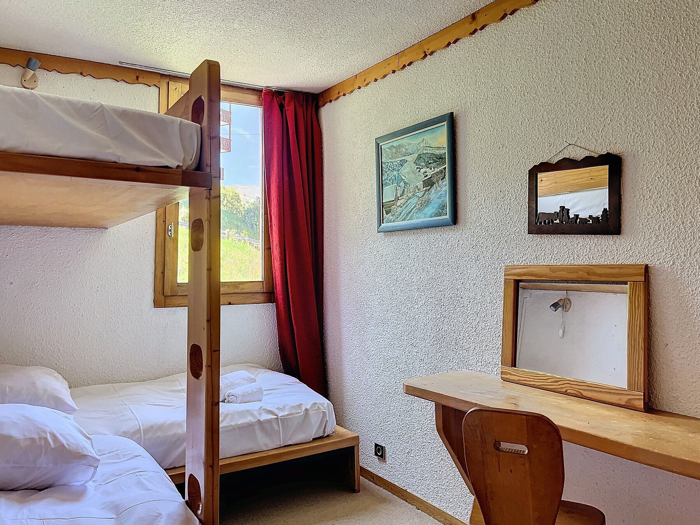 Een slaapkamer met een stapelbed, bureau en spiegel.