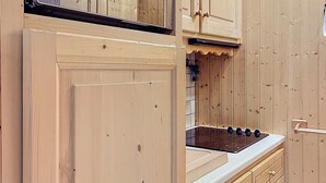 Eine Holz-Küche mit Herd, Schränken und einer Tür.
