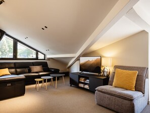 A modern loft-style living room with a sofa, armchair, coffee table, and TV.