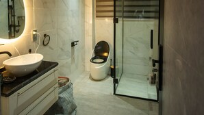 A modern bathroom with a large oval sink, a toilet, and a glass shower enclosure.