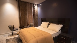 A bedroom with a bed, a nightstand, a chair, and a patterned rug.
