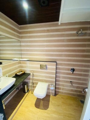 Ein modernes Badezimmer mit gestreifter Wandgestaltung, einem großen Spiegel, einem Waschbecken, einer Toilette und einer Duschkabine.
