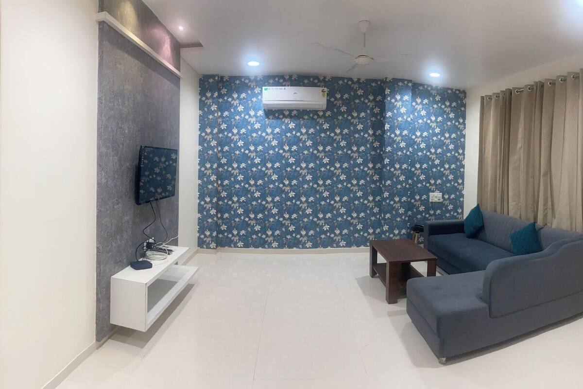 Una sala de estar moderna con un sofá, un televisor y una pequeña mesa.
