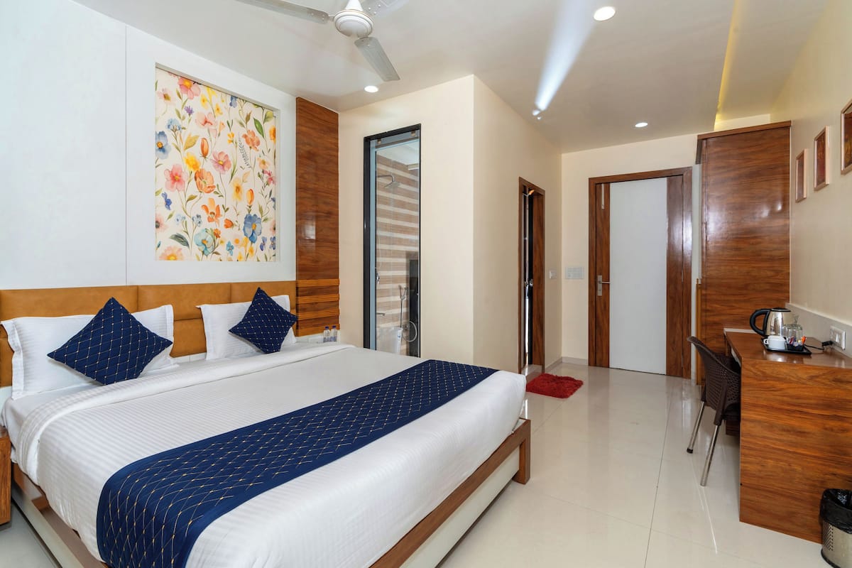 Habitación de hotel con una cama grande, un escritorio, una silla, un ventilador de techo y una puerta.