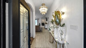 A hallway with a chandelier, a mirror, and a plant on a console table. - Cozy 3-bedroom house in welcoming Arlington with WiFi, AC (Arlington)