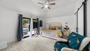 A bedroom with a bed, a chair, a nightstand, a ceiling fan, and a view of the outdoors. - Cozy 3-bedroom house in welcoming Arlington with WiFi, AC (Arlington)