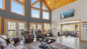 A spacious living room with high ceilings, large windows, and a variety of seating options.